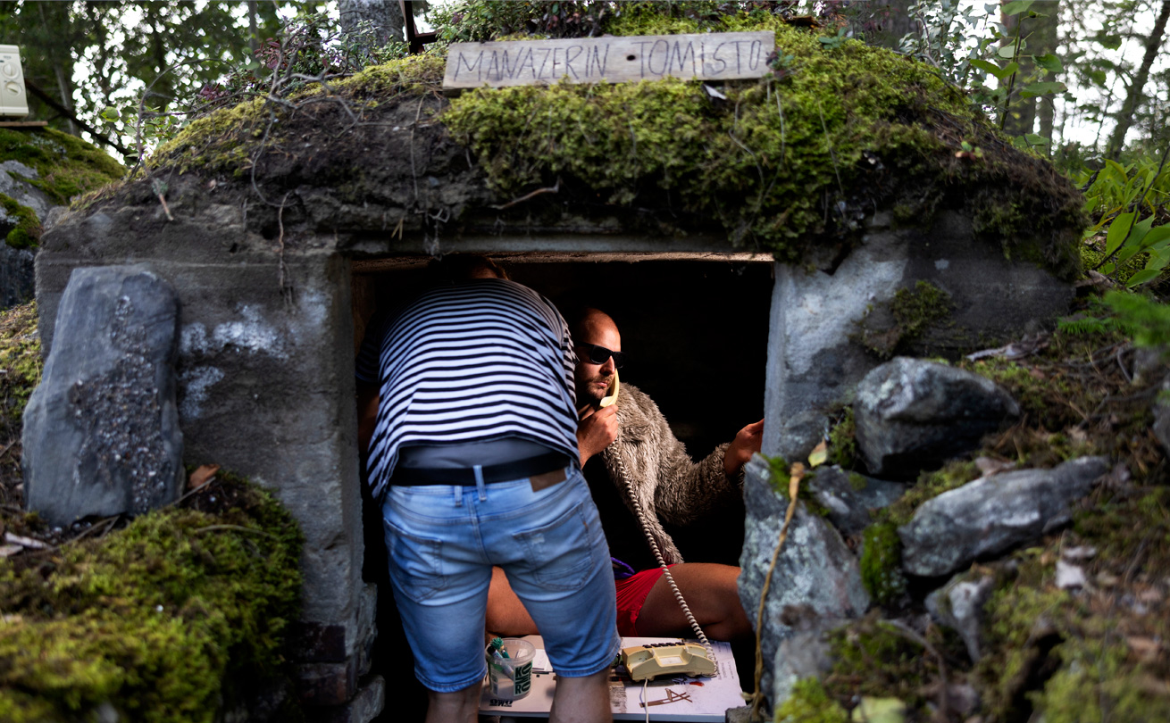 Kuvassa Olli-Pekka Ojansivu vanhassa maakellarissa soittamassa puhelua, kellarin katolla lukee manazerin toimisto, kuvaaja kuvaa häntä.