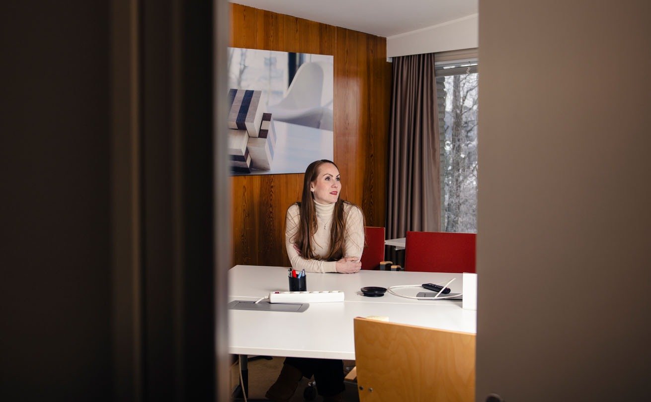 Kurkistus työhuoneeseen, jossa Anni Wahlroos istuu työpöydän ääressä