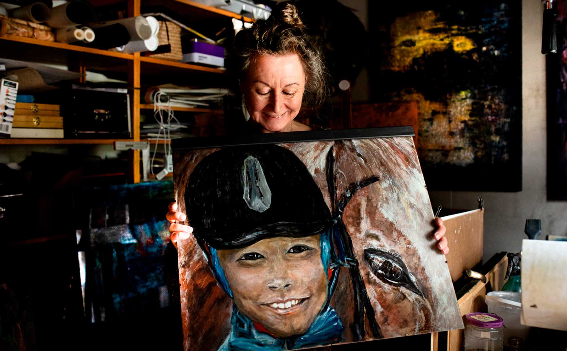 Nainen esittelee taideteosta, jossa on lapsi ja hevonen.