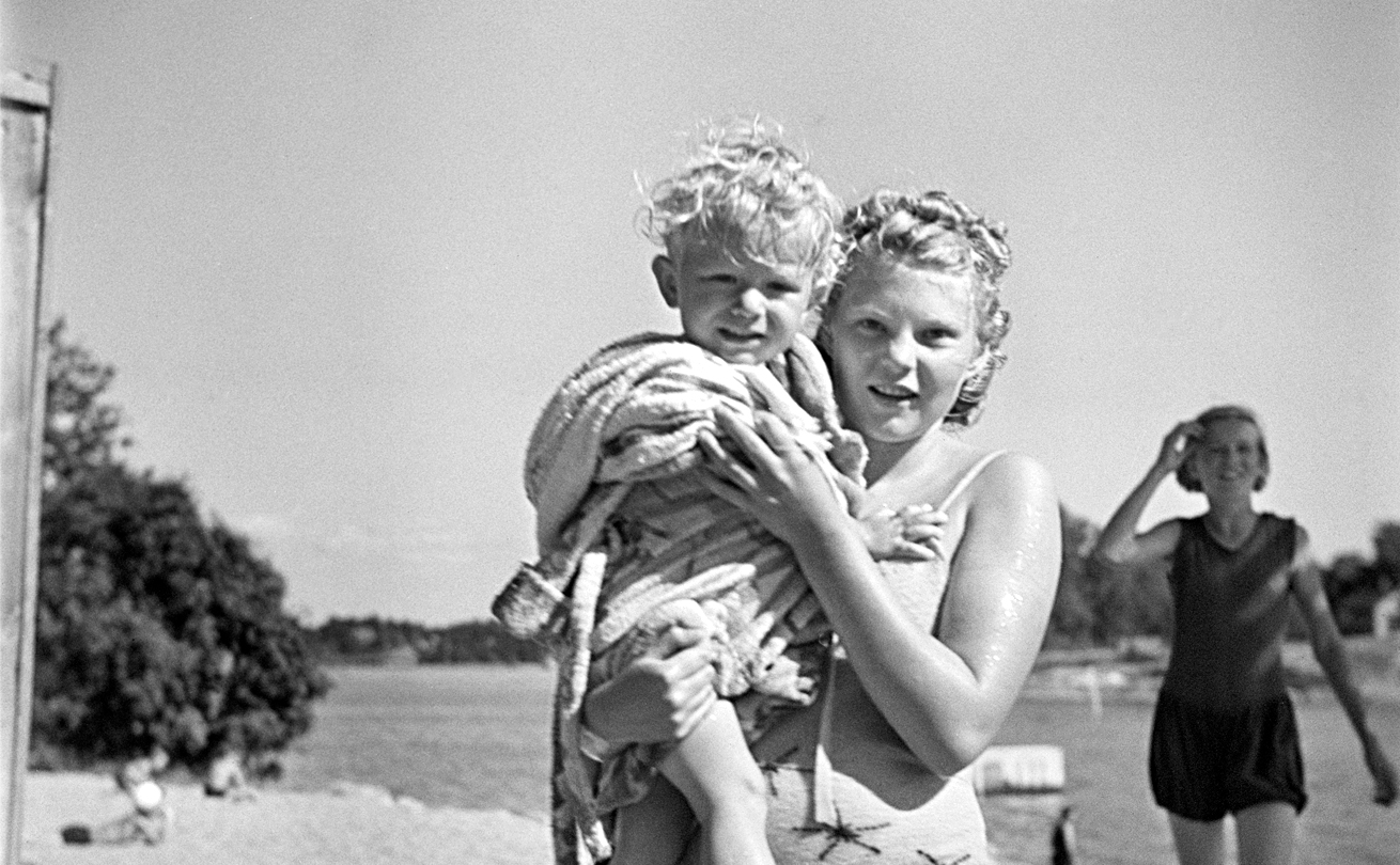 Pikkulapsi ja nuoria naisia rantahiekalla. Tekijä: Heinonen Eino. Ajankohta: 1950 -luku. Helsinki, Sompasaari. Kuva: Helsingin kaupunginmuseo