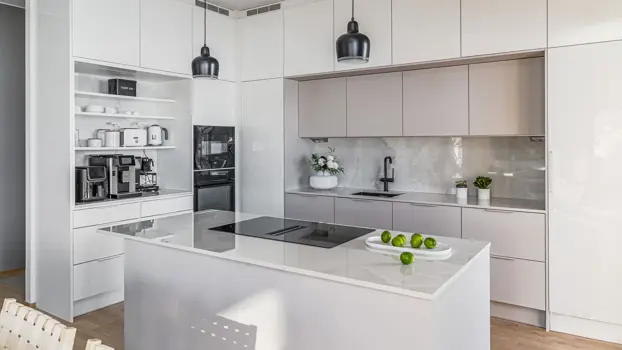 Kuvassa näkyy vaaleasävyinen keittiö, jossa on saareke ja sen päällä limejä.