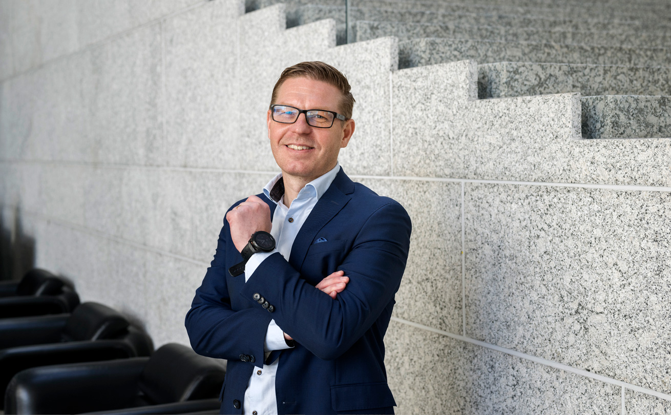OP:n Business Lead Antti Niemelä hymyilee lähikuvassa OP:n pääkonttorin portaikon edessä