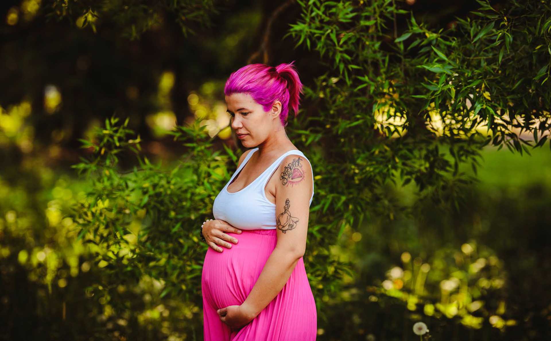 Ida Paarnio pitelee raskausmahaansa pinkissä mekossa.