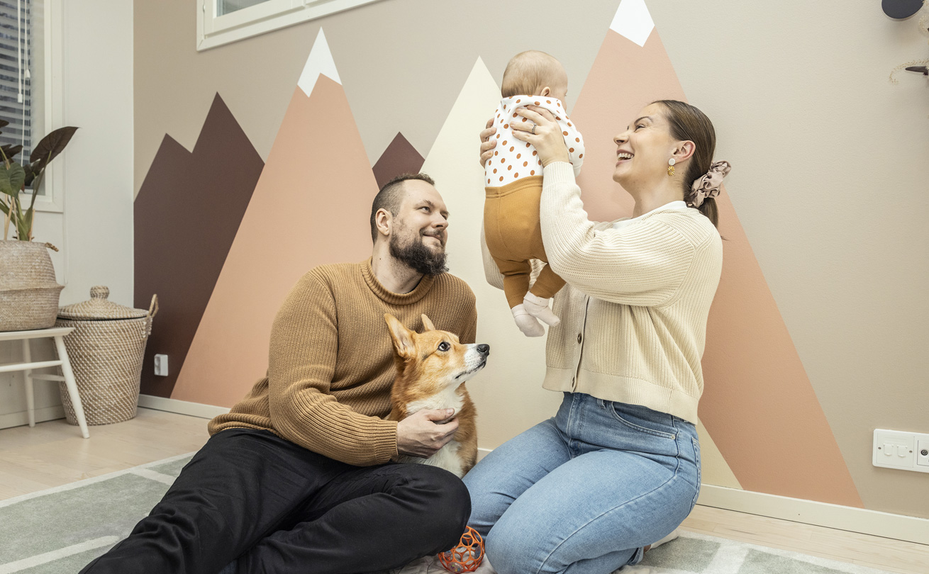 Antti ja Riina Periviita lattialla vauvansa ja Manu-corginsa kanssa.