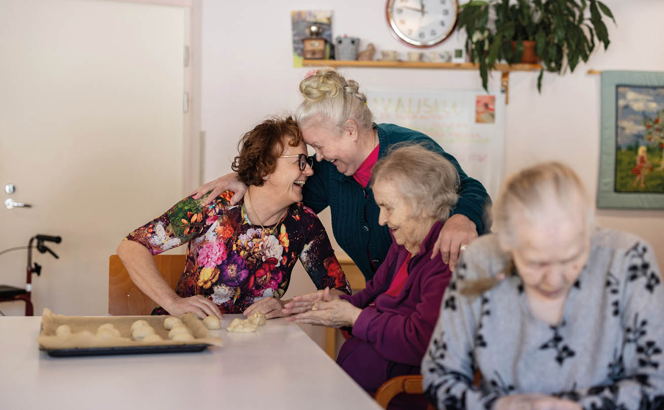 Auli leipomassa asukkaan Meeri Mahlamäen kanssa pullaa. Harmaassa paidassa Helmi Viljanen, turkoosissa neuletakissa Maire Nummela.