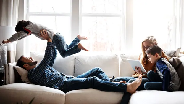 Kuvassa perhe lekottelee mukavasti sohvalla.