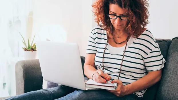 Nainen istuu läppäri sylissään