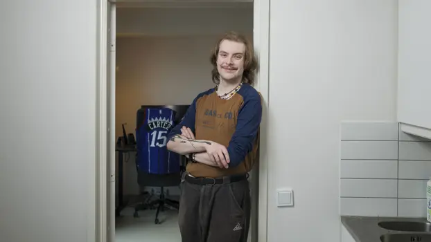 Eino Salma Mervola nojaa ovenkarmiin keittiössä ja hymyilee.