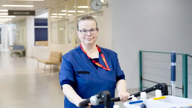 Laitoshuoltaja Outi Korvela työasussaan sairaalan käytävällä.