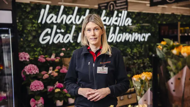 Jenny Niemelä työasussaan K-Citymarketissa, taustalla näkyy kukkaosasto.