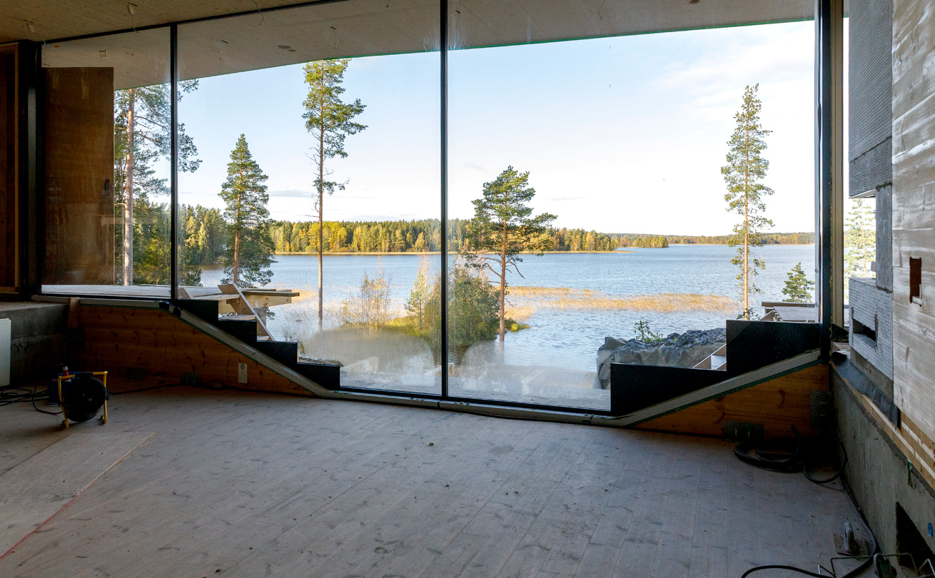 Rakenteilla oleva talon sisätila, josta näkyy ikkunaseinän läpi järvelle.