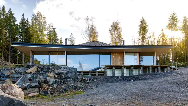 Kuvassa on lasiseinäinen huvila kallion kupeessa.