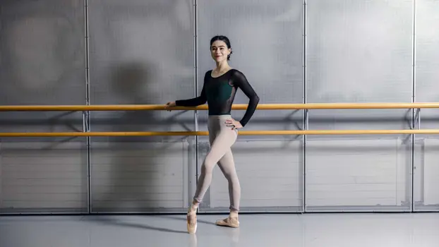 Evelyn Robinson balettiasussaan tanssisalissa, käsi lepää seinään kiinnitetyn kaiteen päällä.