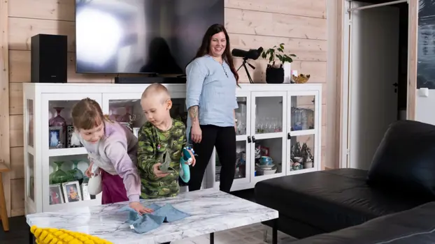 Pienimmät lapset Saga ja Ahti auttavat Katja Varista siivoamisessa. Saga pyyhkii olohuoneen pöytää ja Ahdilla kädessä puhdistusainepullo, taustalla Katja-äiti.