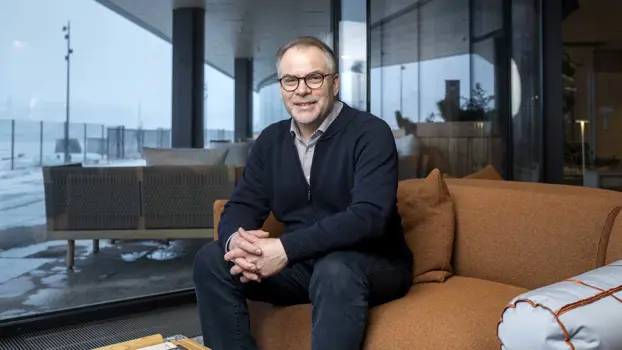 Aarno Dietz istuu sohvalla ja pitelee polveaan.