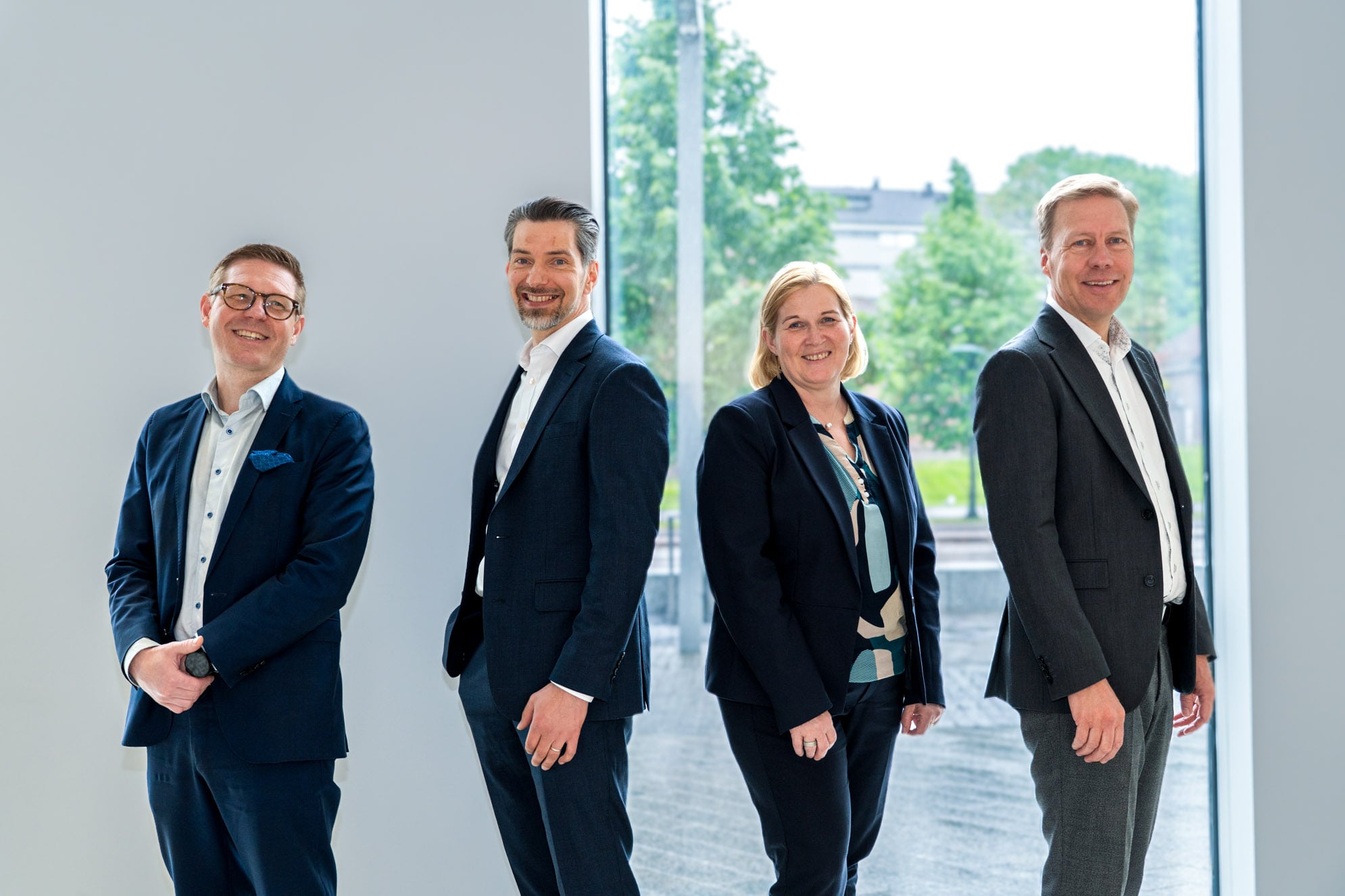 Antti Niemelä, Tuomas Haapakoski, Marika Toikka ja Jussi Haarasilta seisovat hymyillen OP Pohjolan Vallilan konttorin aulassa.