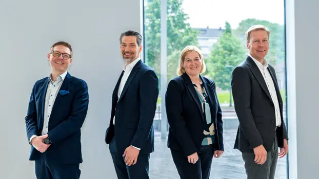 Antti Niemelä, Tuomas Haapakoski, Marika Toikka ja Jussi Haarasilta seisovat hymyillen OP Pohjolan Vallilan konttorin aulassa.