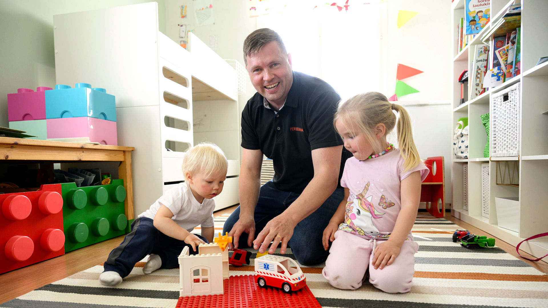 Markku Nenonen lattialla kahden lapsensa kanssa.