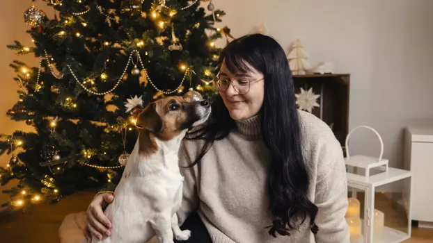 Jasmin istuu Karpo-koiran kanssa joulukuusen edessä.