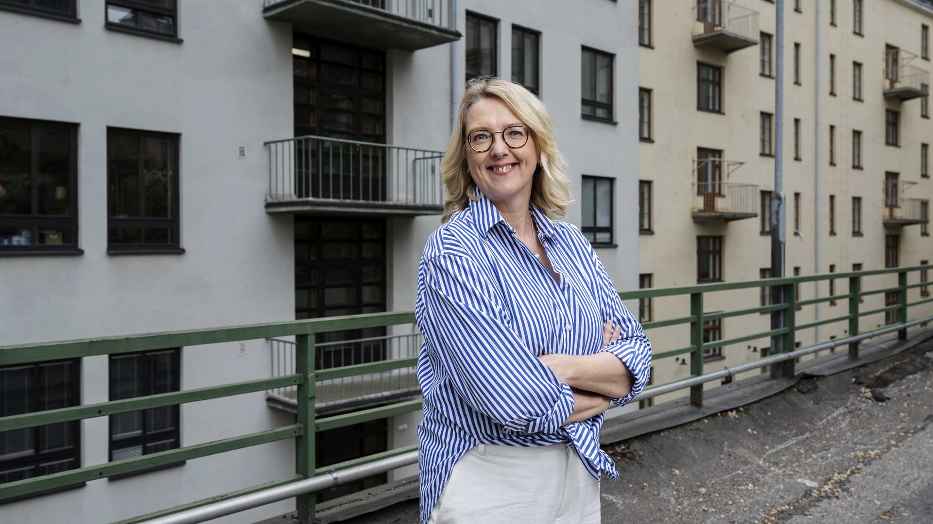 Emilia Kullas hymyilee kädet puuskassa kerrostalon sisäpihalla.