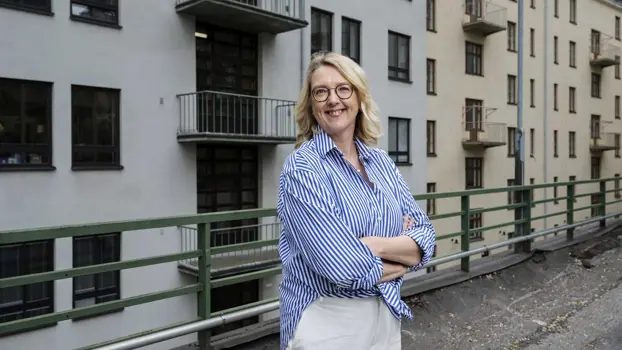 Emilia Kullas hymyilee kädet puuskassa kerrostalon sisäpihalla.