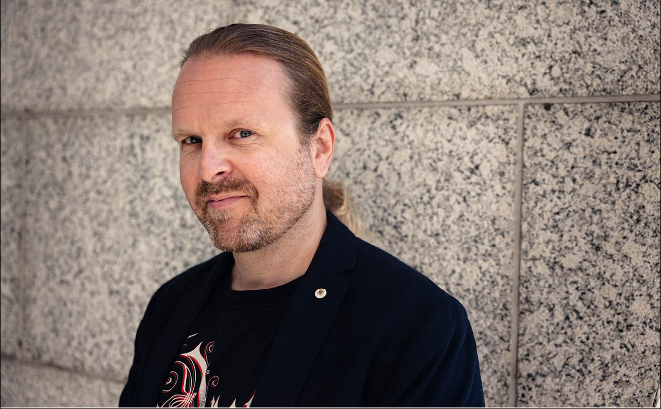 Ville Pekkala katsoo kuvaajaan, taustalla näkyy graniittista seinämää.